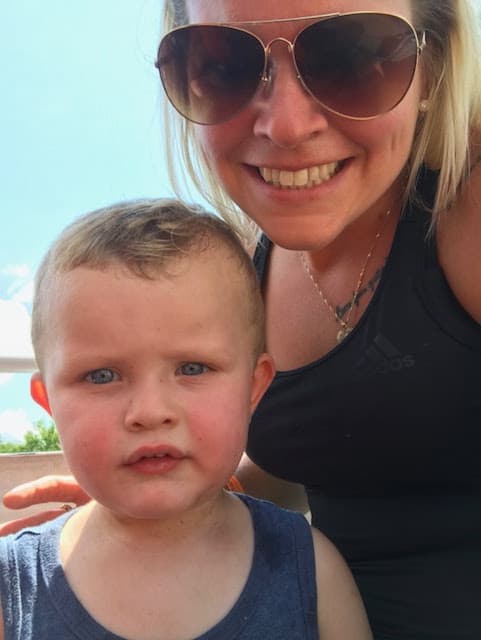 Un selfie au soleil de Rafaël et de sa maman, son bras autour de lui, tous les deux face à la caméra.